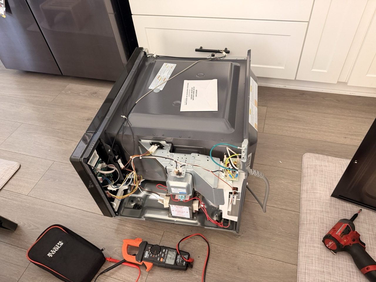 Era Service technician diagnosing a microwave with a multimeter in the Inland Empire