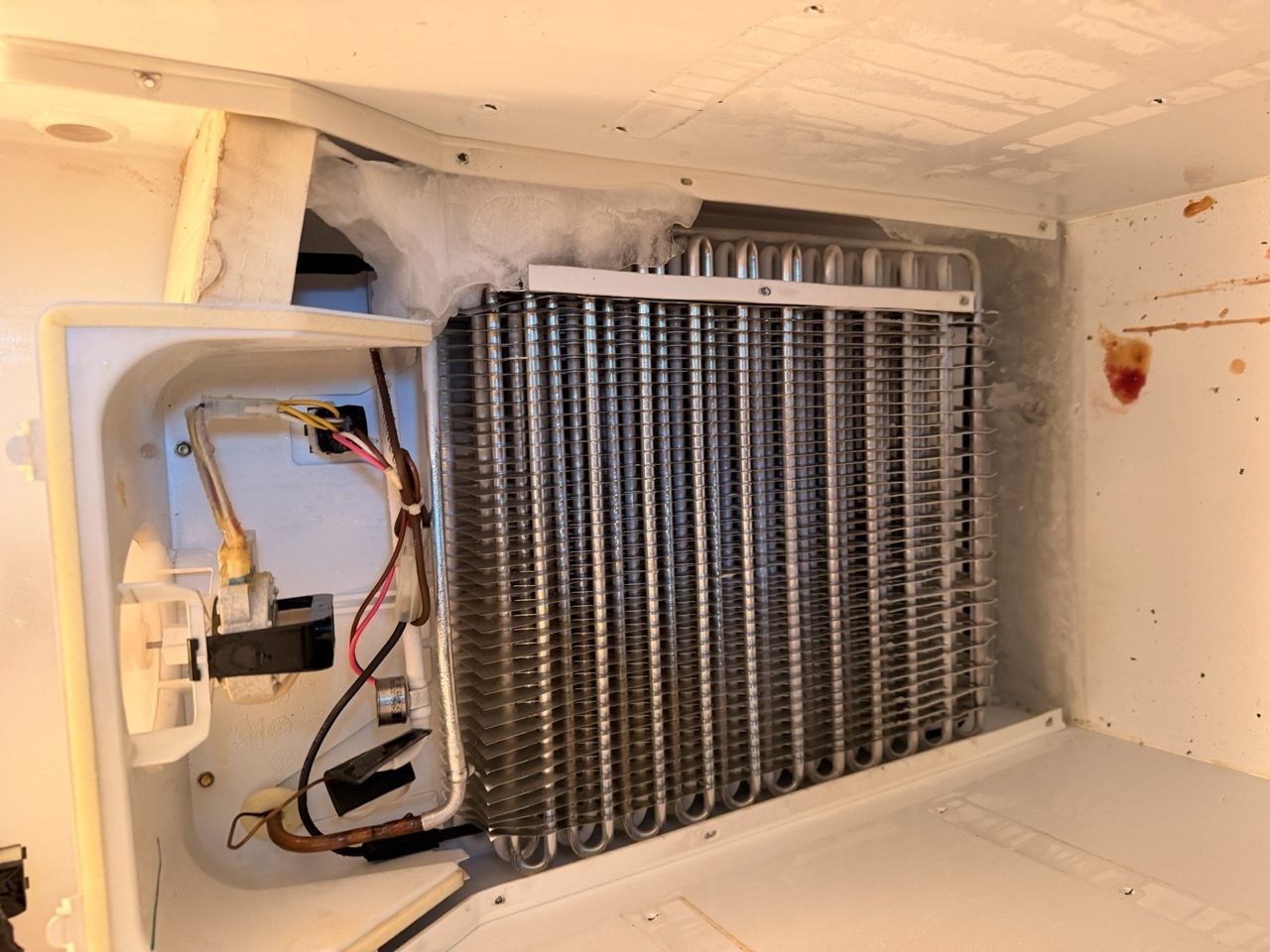 Exposed evaporator coils during a refrigerator repair by an Era Service technician in the Inland Empire