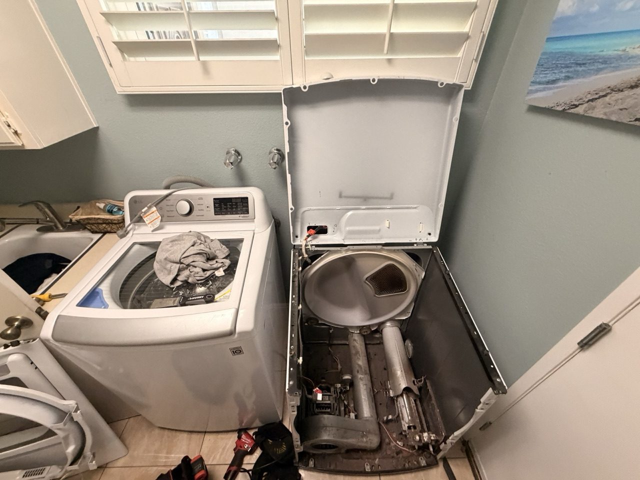 Era Service technician repairing a dryer with the cabinet opened in a the Inland Empire laundry room